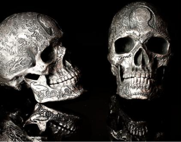 Two engraved silver-finish skulls on a black background