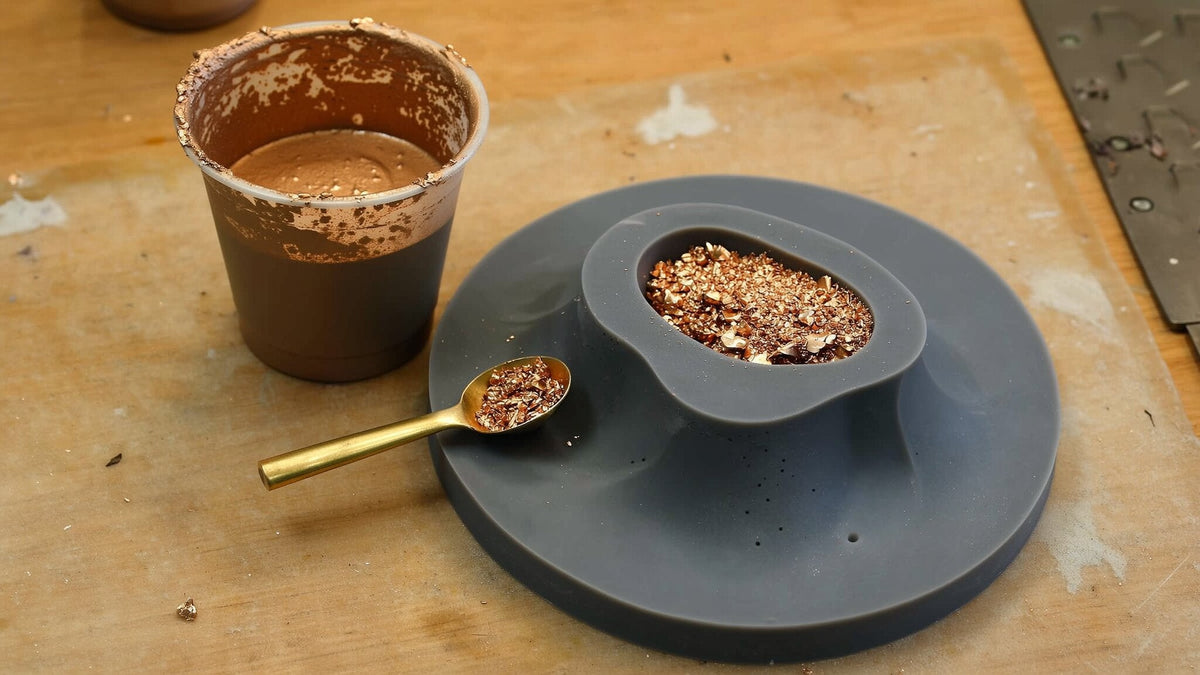 Resin tinted with bronze powder beside a silicone mold and a small scoop
